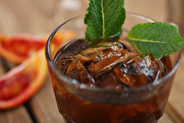 Cóctel whisky cola con hielo en un vaso. sobre una tabla de madera ...