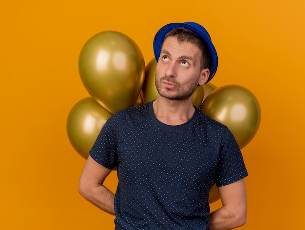 Confundido apuesto hombre caucásico con gorro de fiesta azul sostiene