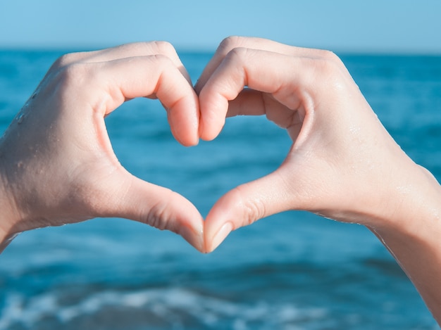 Corazón de manos en la playa | Foto Premium
