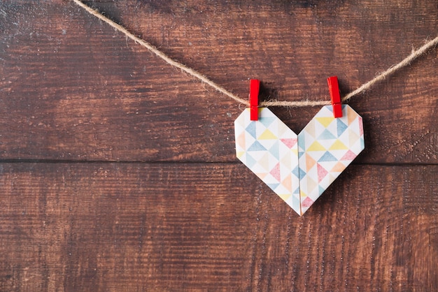 Corazón de papel con alfileres enganchados en hilo. Foto gratis