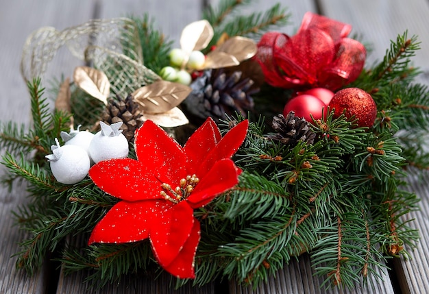 Corona de navidad decorada con bolas rojas luces y piñas sobre un