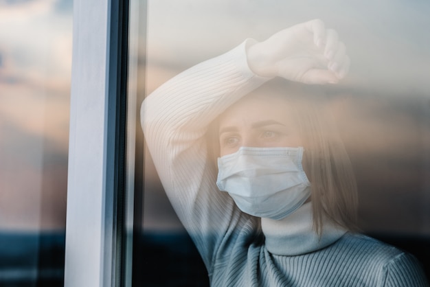 Coronavirus. mujer enferma con mascarilla de protección mirando por la  ventana. paciente aislado en casa para prevenir infección. sala de  cuarentena en el hospital. | Foto Premium