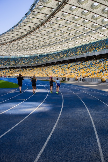 Corridas de deportistas en la pista azul vacía en el estadio olímpico