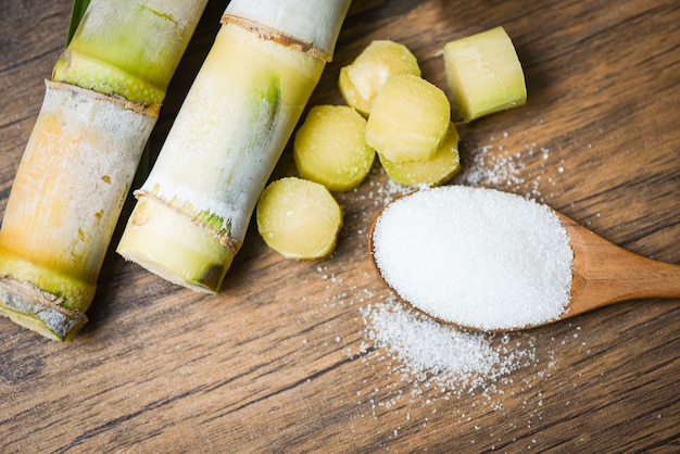 Cortar el pedazo de caña de azúcar y el azúcar blanco en una cuchara de  madera | Foto Premium