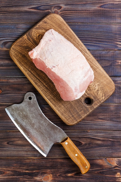 Corte crudo del hombro de cerdo a bordo con cuchillo o hacha de cocina