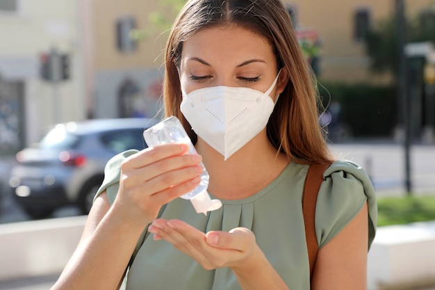 Covid-19 coronavirus pandémico primer plano mujer con máscara ffp2 usando alcohol gel desinfectante manos en la calle de la ciudad. Foto Premium 