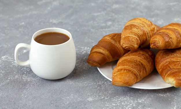 Croissants recién horneados y una taza de café en la mesa de piedra