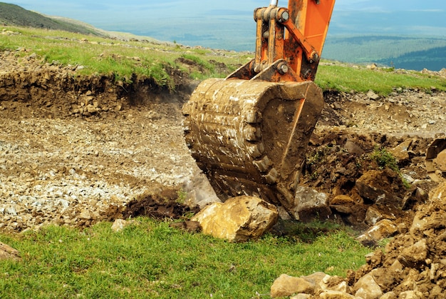 El cucharón de una excavadora en funcionamiento arranca la hierba y la