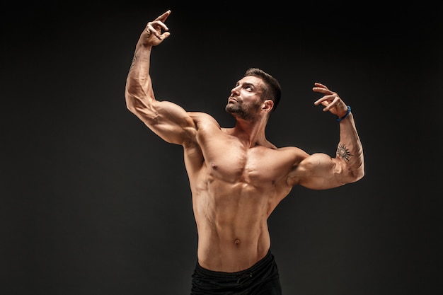 Culturista Posando Hombre Musculoso Fitness En Pared Oscura Foto Premium