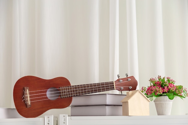 Decoración en dormitorio con mini guitarra y libro con flor. | Foto Premium