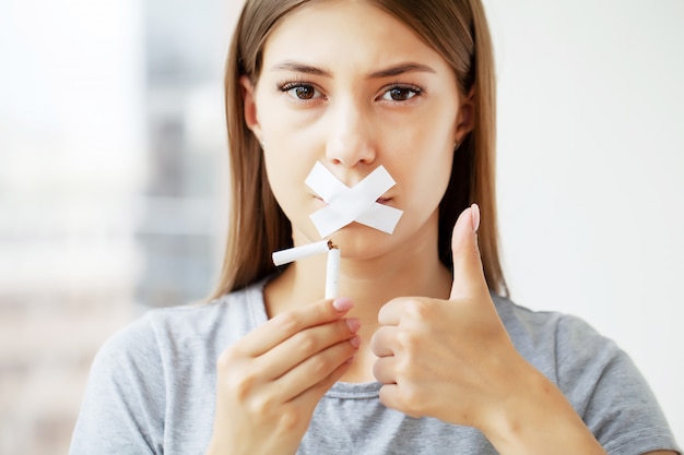 Deje de fumar, una mujer joven comunica su posición sobre la nocividad de los cigarrillos. Foto Premium 