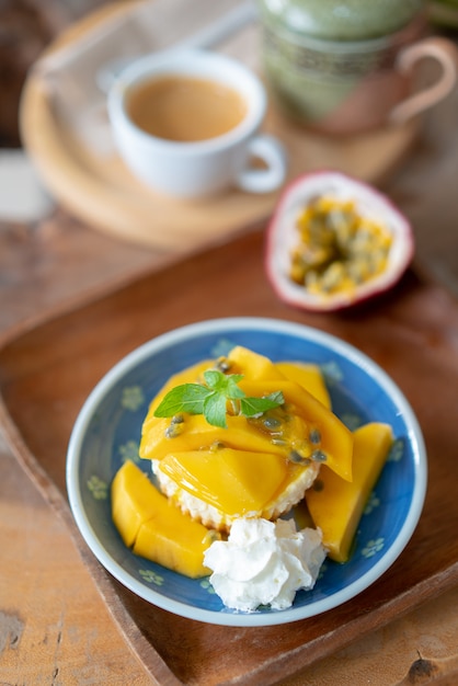 Deliciosa tarta de queso con maracuyá y mango en mesa de madera. Foto Premium