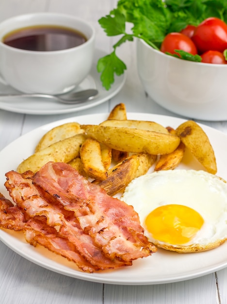 Desayuno con tocino, huevo frito, papa y taza de café