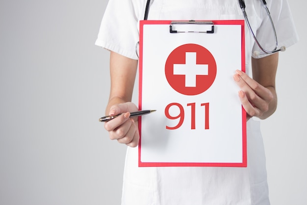 Detalle de un médico con estetoscopio sosteniendo un portapapeles con el icono de cruz médica. señal de llamada de emergencia. llame al 911 ambulancia. ilustración de emergencia médica. en el fondo blanco. Foto gratis