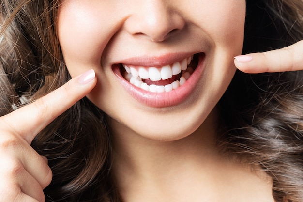 Los dientes sanos perfectos sonríen de una mujer joven. blanqueamiento dental. clínica dental paciente. la imagen simboliza la odontología del cuidado bucal, la estomatología. Foto Premium 