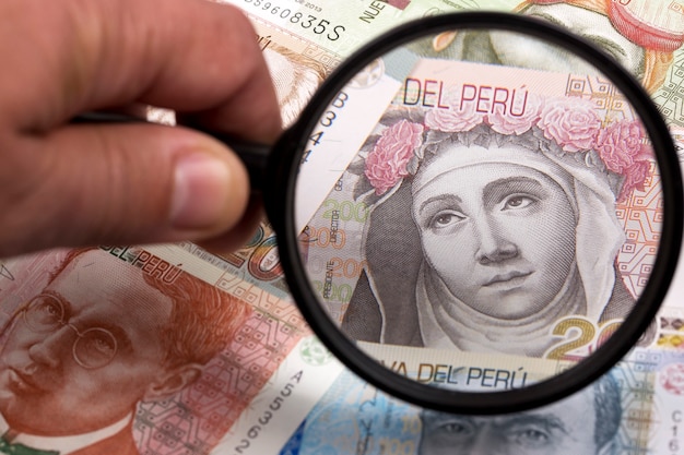 Dinero peruano en una lupa un trasfondo empresarial Foto Premium