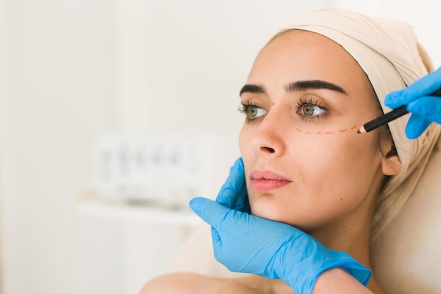 Doctor Dibujando Marcas En La Cara Femenina Contra El Fondo Blanco Foto Premium