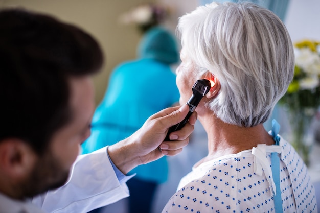 Doctor examinando el oído del paciente con otoscopio Foto Premium