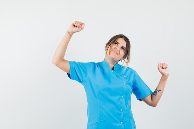 Doctora Mostrando Gesto Ganador En Uniforme Azul Y Mirando Feliz | Foto ...