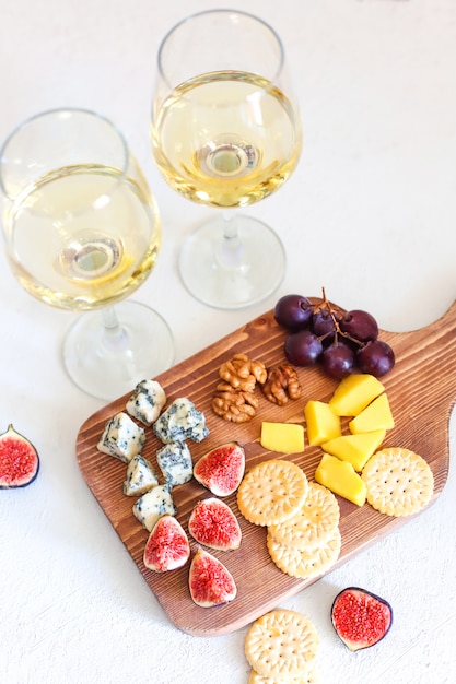 Dos copas de vino blanco y tabla de quesos con nueces ...