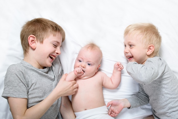 Dos Hermanos Mayores Juegan Y Rien Con El Bebe Mas Pequeno En Una