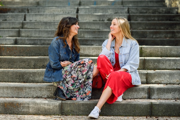 Dos mujeres jÃ³venes hablando y riendo en pasos urbanos.