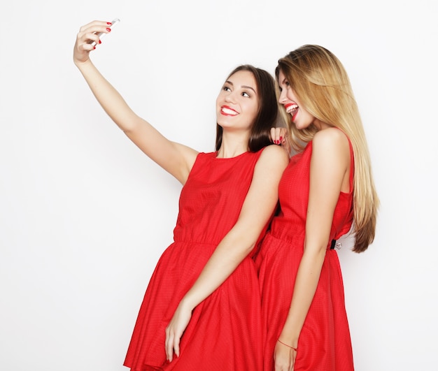 Dos Mujeres Jóvenes Con Vestido Rojo Tomando Selfie Con Teléfono Móvil Foto Premium