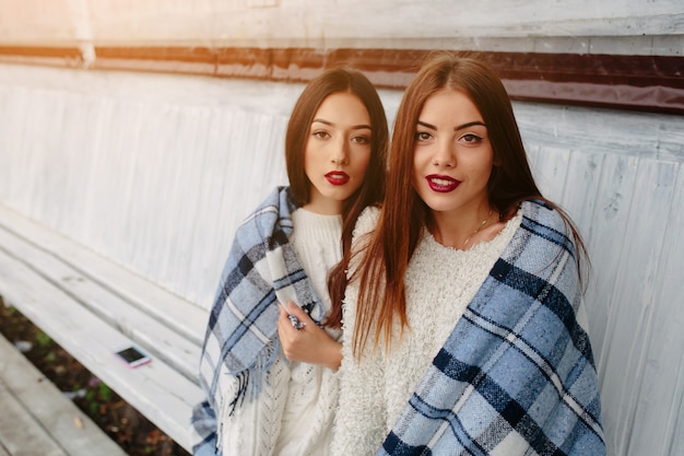 Dos Mujeres Se Sientan En Un Banco En El Parque Y Posando Foto Gratis