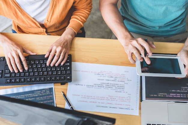 Dos programadores profesionales que cooperan y trabajan en el proyecto del sitio web en un software que se desarrolla en computadoras de escritorio en la empresa, códigos y códigos de datos de escritura, programación con html, php y javascript Foto Premium