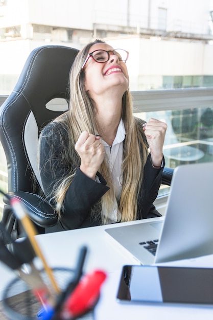 Empresaria Joven Emocionada Que Se Sienta En El Lugar De Trabajo Foto