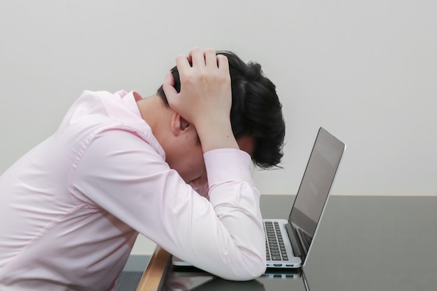 Empresario estresado agarrando su cabeza frente a una computadora portátil con síndrome de burnout | Foto Premium