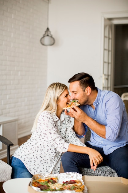 Encantadora Joven Pareja Comiendo Pizza En La Habitación Foto Premium