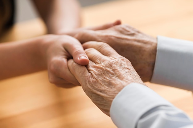 Enfermera sosteniendo las manos del hombre mayor de empatía Foto gratis