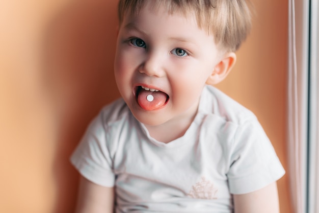 Enfoque selectivo en una píldora blanca en una lengua de un niño ...