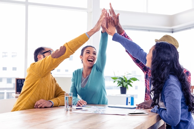 Equipo alegre del negocio que hace el alto cinco mientras que se sienta en oficina creativa Foto Premium
