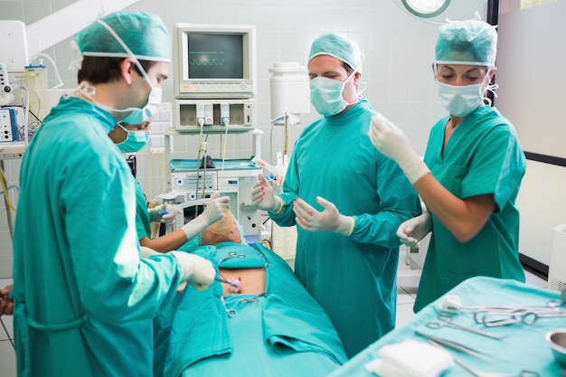 equipo de cirugía operando a un paciente en un quirófano foto premium