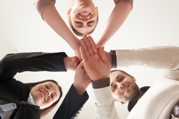 Un equipo de negocios unidos exitoso juntó las manos, vista desde abajo Foto gratis