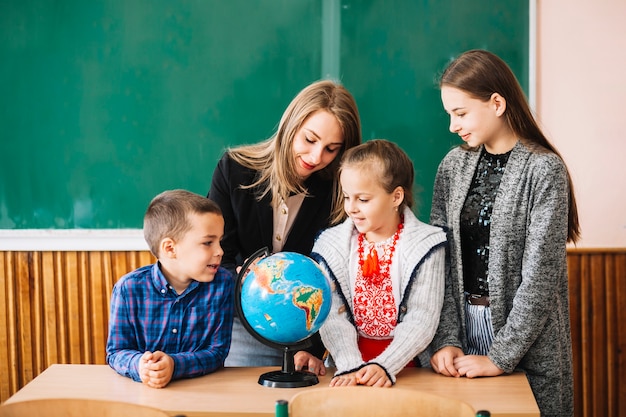 Estudiantes y maestro de escuela mirando mundo | Foto Gratis