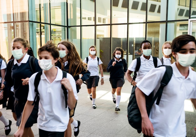 Los estudiantes de secundaria con máscaras en su camino a casa Foto gratis