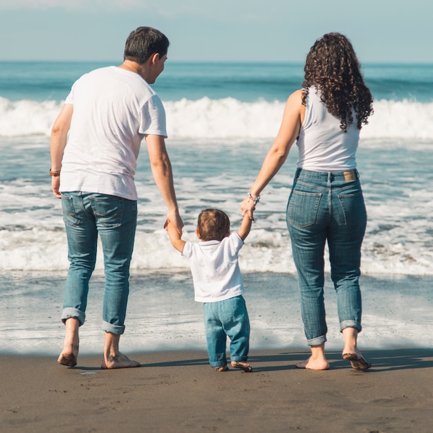 Familia Feliz Con El Bebe Caminando En La Playa Y Mirando El Mar Foto Gratis