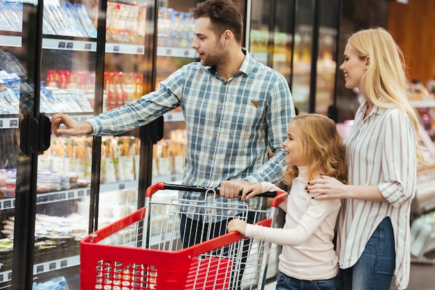 Familia feliz con niño y carrito de compras comprando comida Foto Gratis