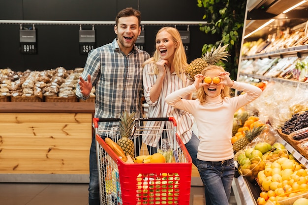 Familia feliz con niño comprando comida en la tienda de ...