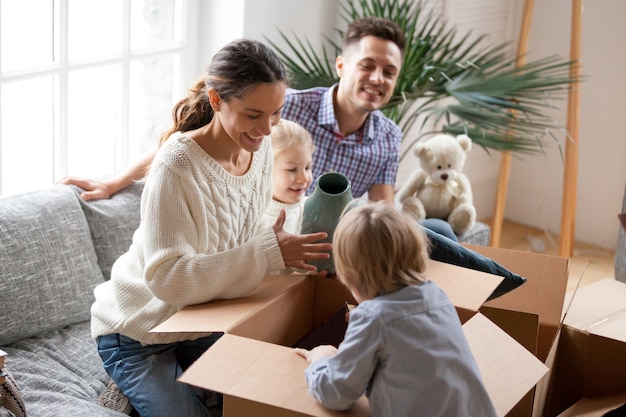 Familia feliz con niños desempacando cajas que se mudan a su nuevo hogar Foto gratis