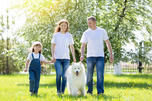 Familia Feliz Con Un Perro Blanco En Un Parque De Verano Foto Premium