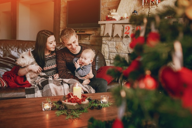  Familia feliz sentada en el sof con un rbol de navidad 