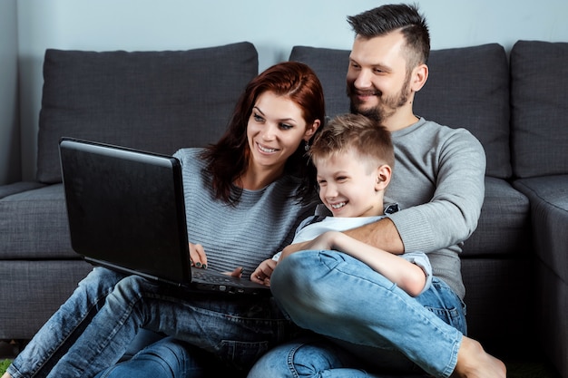 Una familia feliz con sonrisas viendo algo en una computadora portátil Foto Premium 