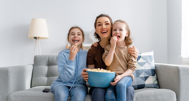 Familia feliz viendo televisión películas con palomitas de maíz por la