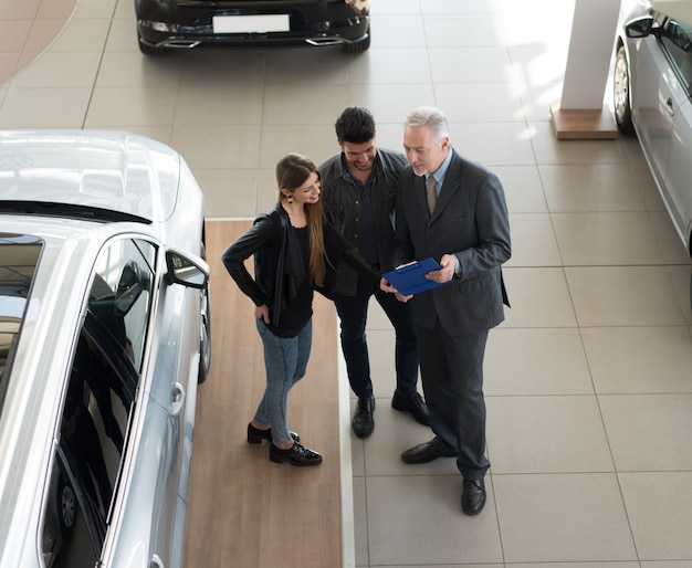 Familia Hablando Con El Vendedor Y Eligiendo Su Auto Nuevo En Una Sala De Exposición Foto Premium 