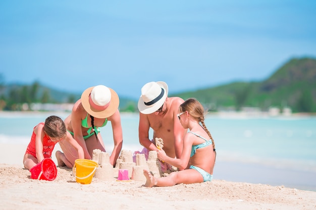 Familia haciendo castillos de arena en la playa tropical blanca Foto Premium 