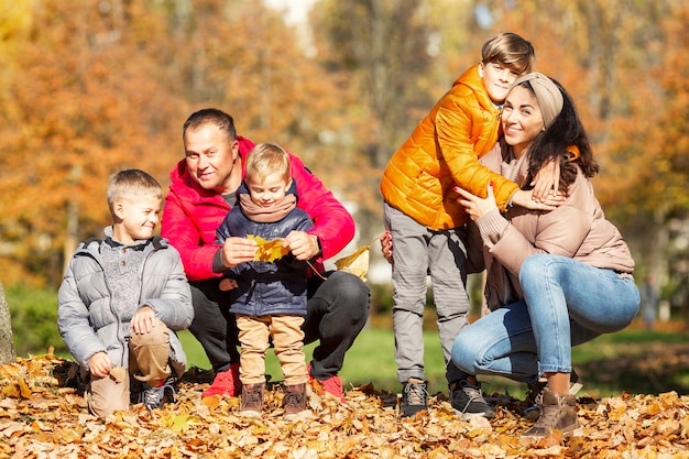 Familia joven feliz con tres hijos en el parque de otoño amor y ternura camina en la temporada